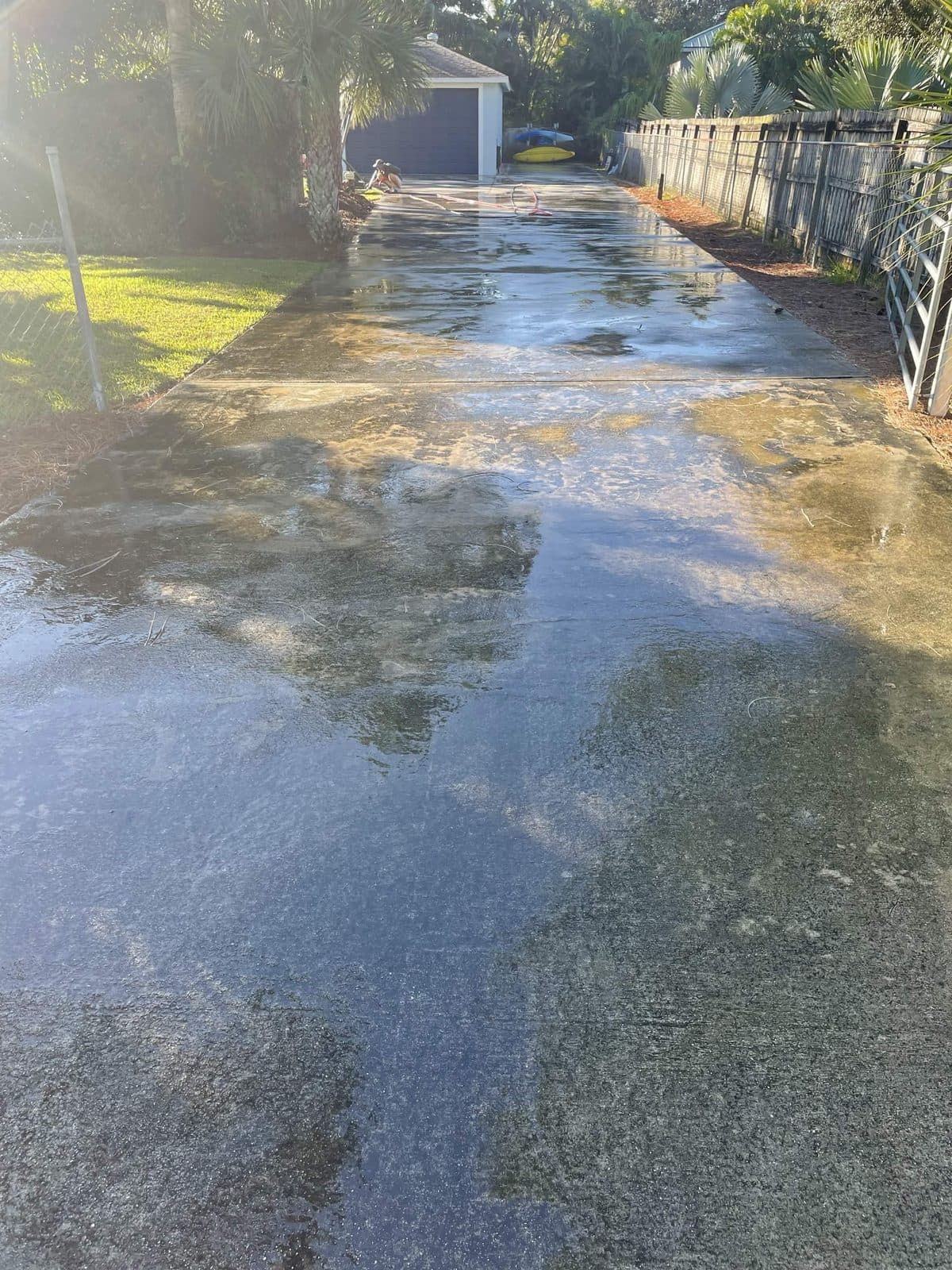 Concrete driveway streaked with grime and green weathering before pressure washing in Loxahatchee FL