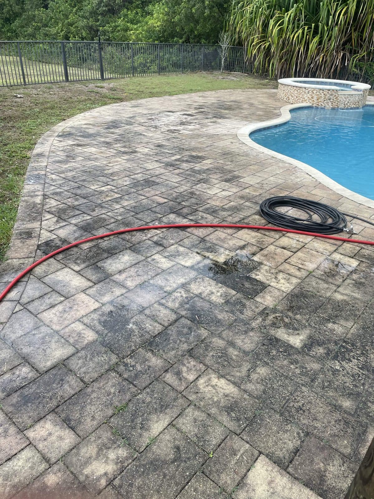 Paver pool deck darkened with mildew before pressure cleaning in Royal Palm Beach FL