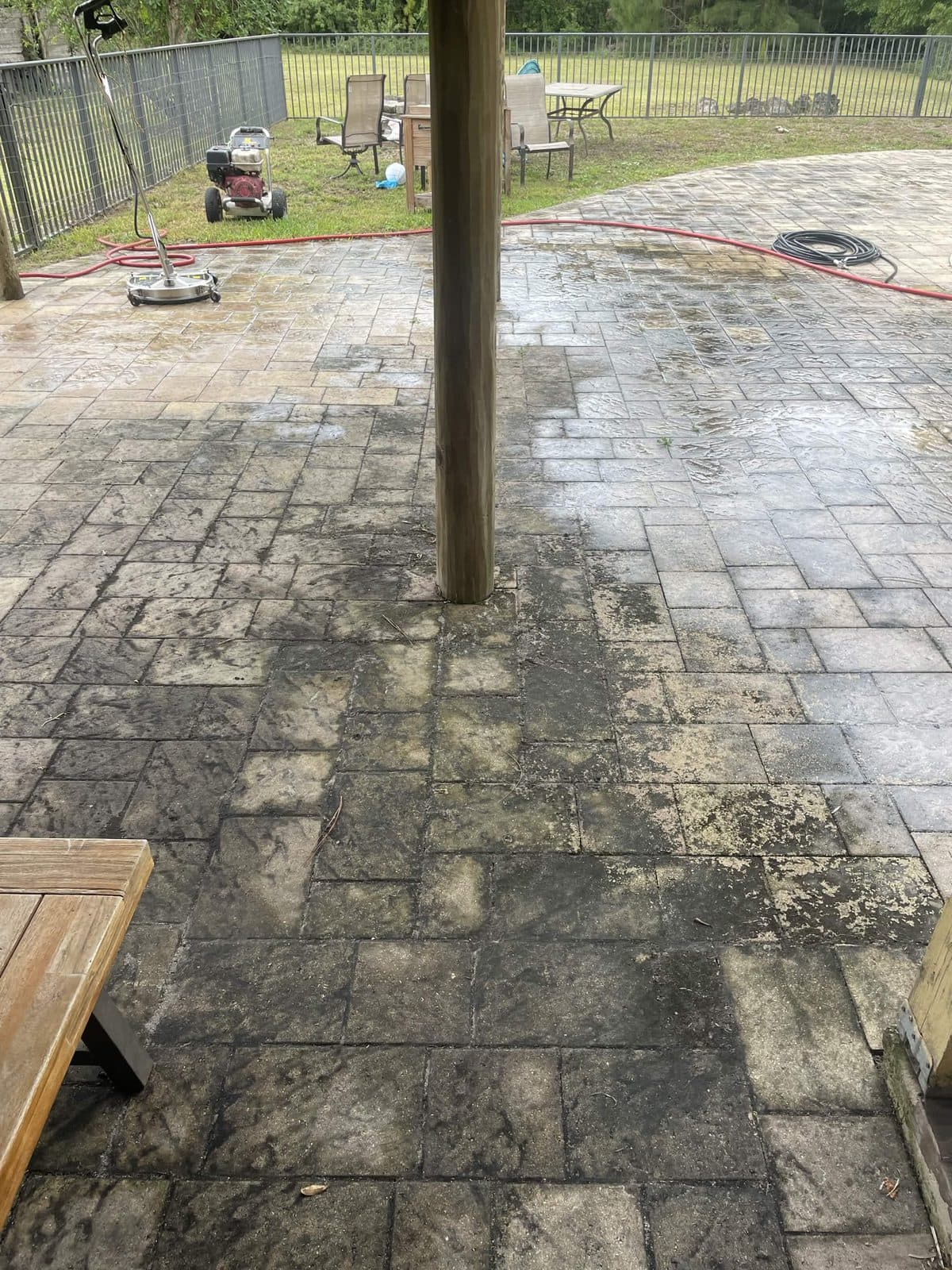 Backyard paver patio black with ground in grime and mildew before pressure cleaning in Lake Worth FL