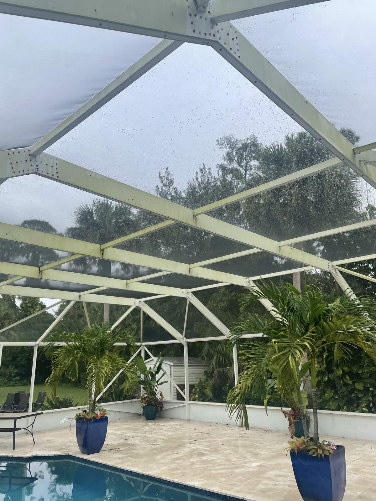 Screen enclosure with a streaked gray frame and dulled screens before a wash in Royal Palm Beach FL